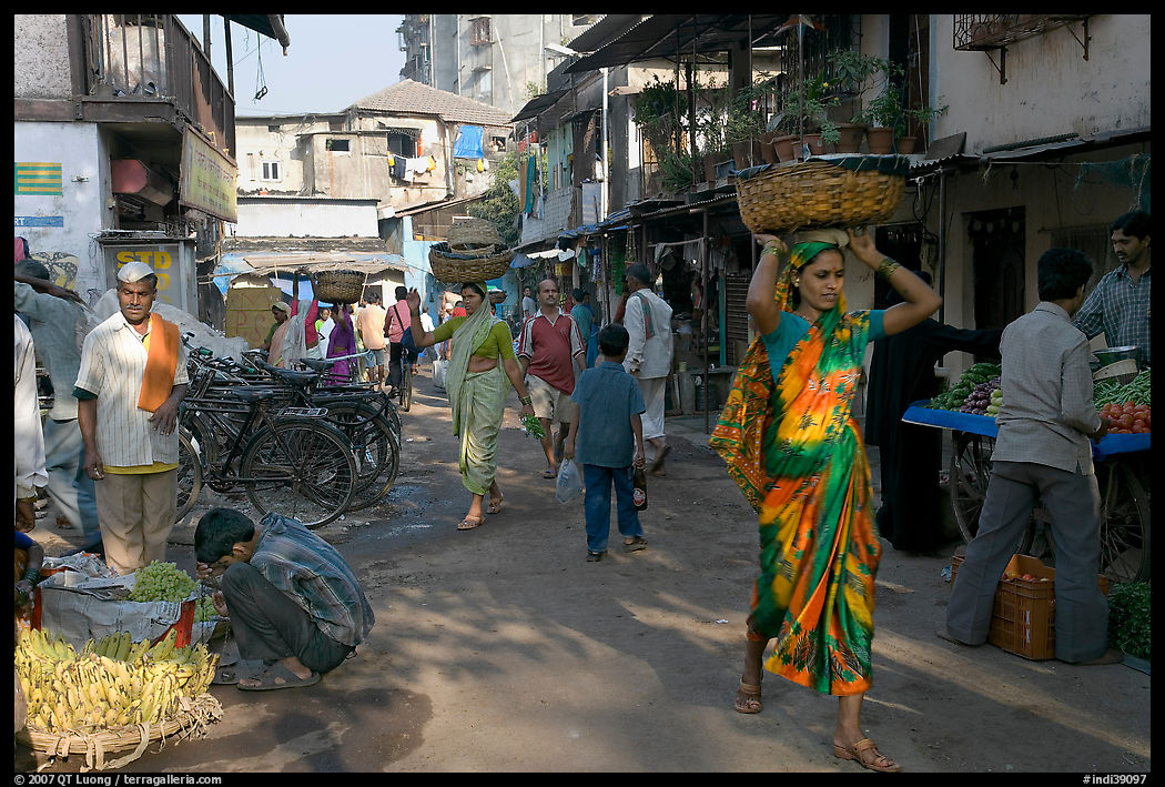 Women carrying  baskets on head in narrow street, Colaba Market. Mumbai, Maharashtra, India