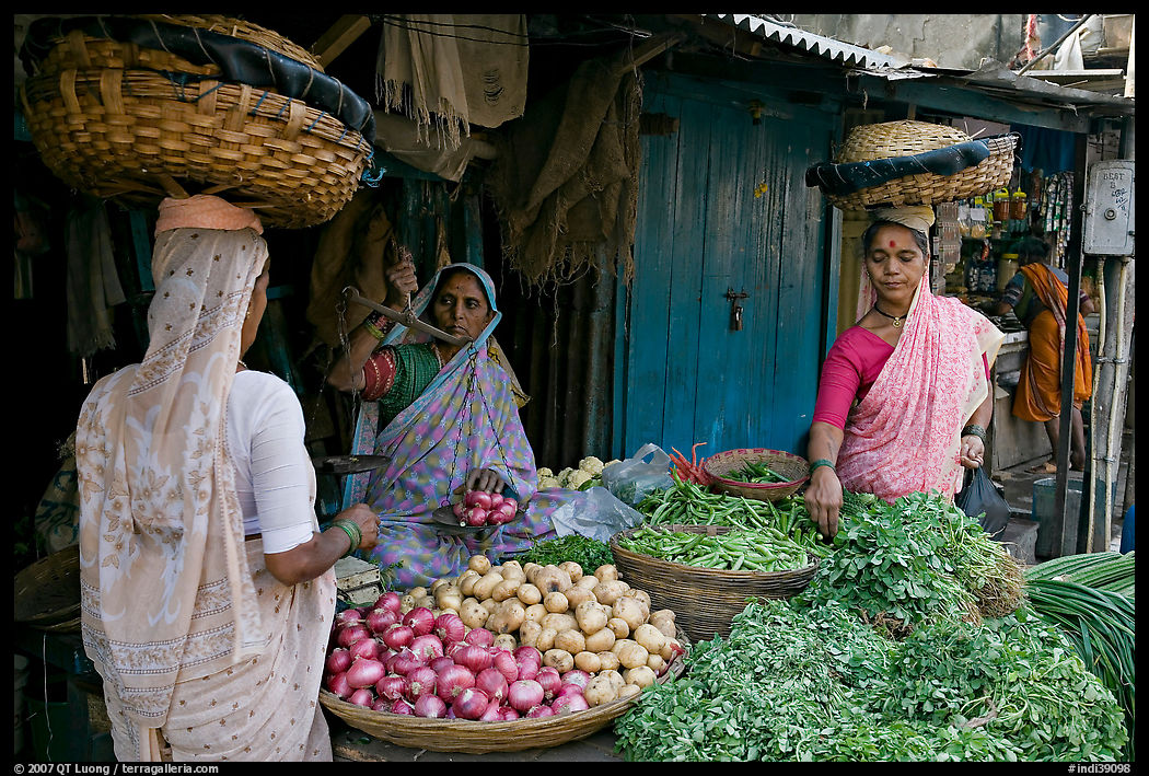 Women with baskets on head buying vegetables, Colaba Market. Mumbai, Maharashtra, India
