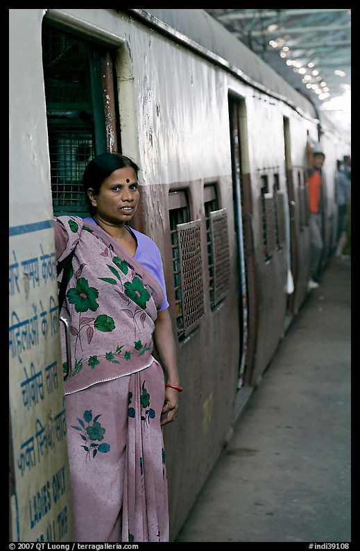 Woman standing at door of suburban train. Mumbai, Maharashtra, India