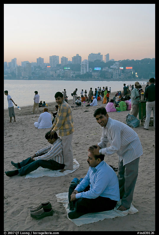 Head masseurs and Mumbai skyline at sunset,  Chowpatty Beach. Mumbai, Maharashtra, India
