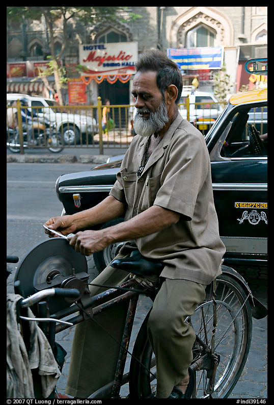 Man sharpening knifes on the street, Colaba. Mumbai, Maharashtra, India