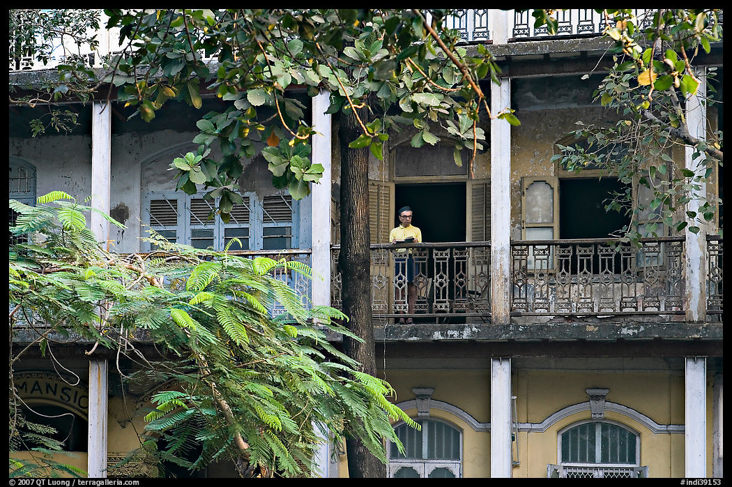 Facade with balconies and man reading. Mumbai, Maharashtra, India