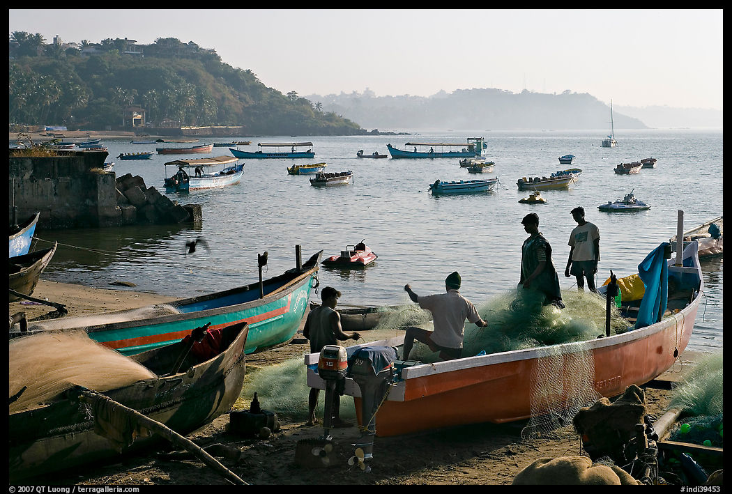 Men repairing net in small fishing boat, early morning, Dona Paula. Goa, India