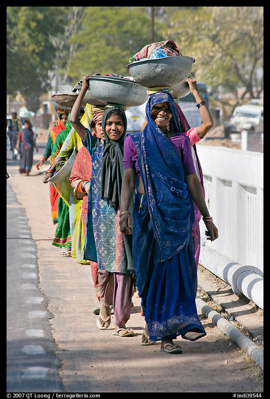 Women walking in line carrying baskets on heads. Khajuraho, Madhya Pradesh, India