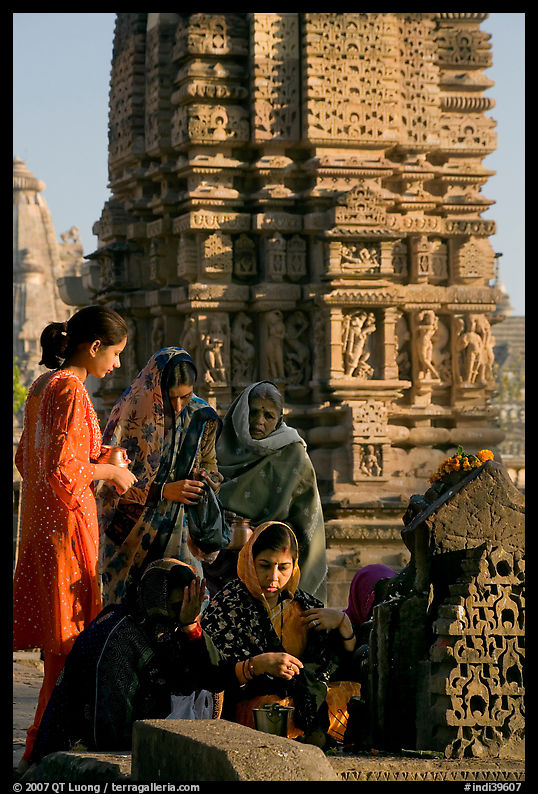 Women offering morning puja  in front temple spire. Khajuraho, Madhya Pradesh, India