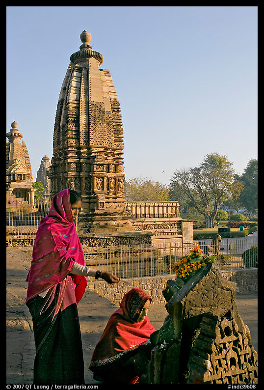 Women worshipping image with temple spire behind. Khajuraho, Madhya Pradesh, India