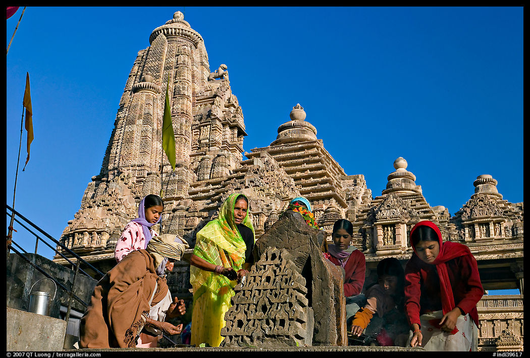 Worshippers making offering with Lakshmana temple behind. Khajuraho, Madhya Pradesh, India