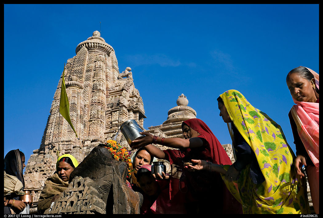 Hindu women making offerings to image with Lakshmana temple behind. Khajuraho, Madhya Pradesh, India
