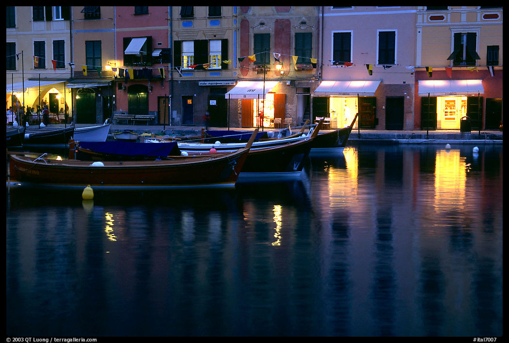 Expensive shops lights reflected in harbor at dusk, Portofino. Liguria, Italy