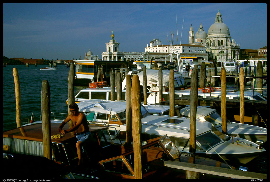 Water taxi driver cleaning out his boat in the morning, Santa Maria della Salute in the background. Venice, Italy