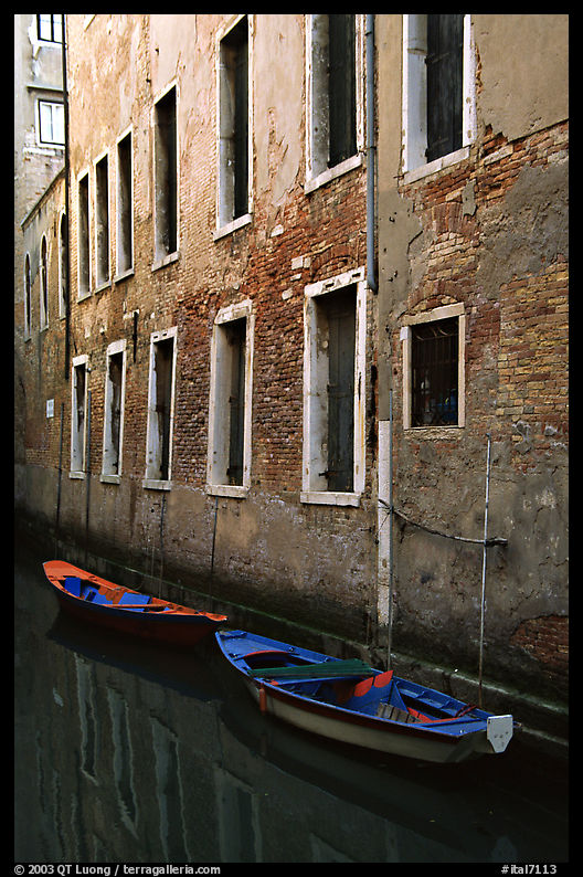 Small boats moored along a wall in a small side canal. Venice, Veneto, Italy