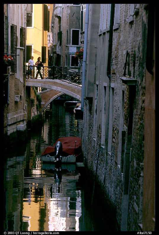 Pedestrians on a bridge over a narrow canal. Venice, Italy