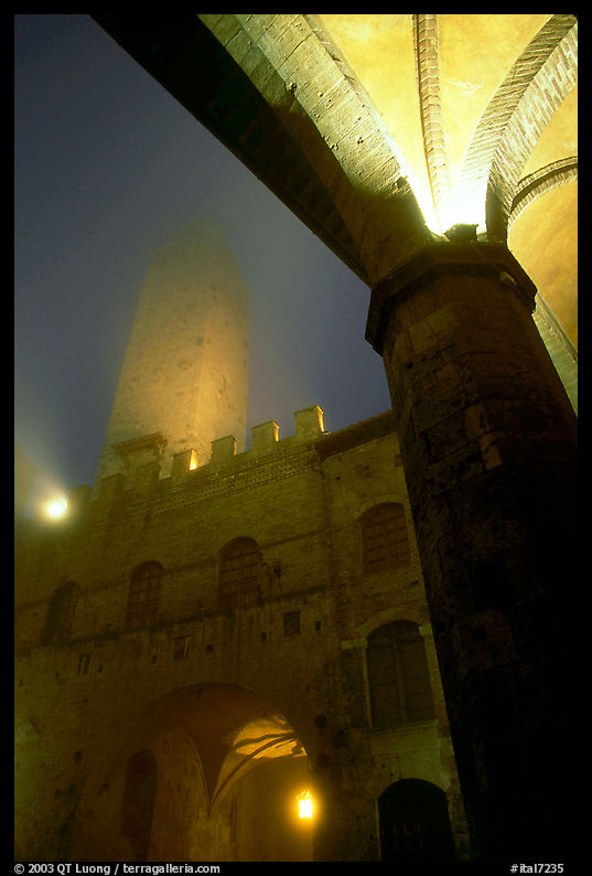 Medieval towers above Piazza del Duomo, foggy night. San Gimignano, Tuscany, Italy