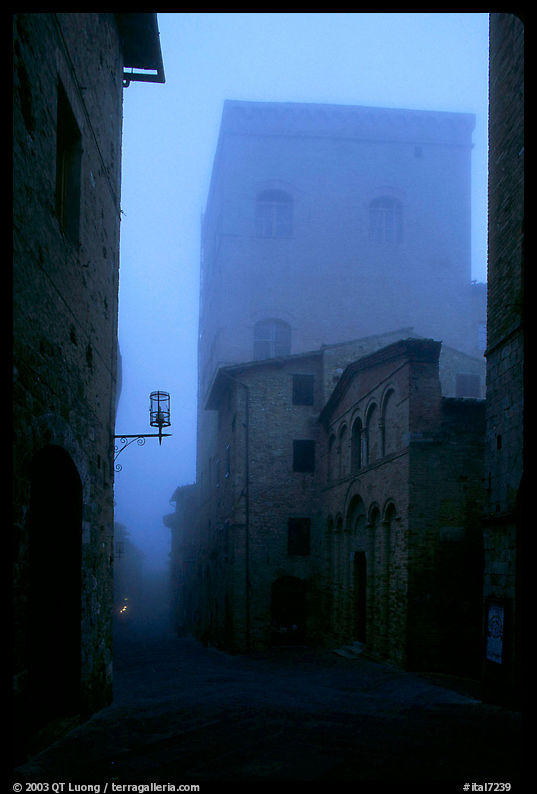Street and medieval tower at dawn in the fog. San Gimignano, Tuscany, Italy