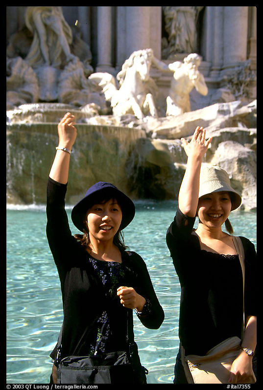 Asian tourists toss a coin over their shoulder into the Trevi Fountain. Rome, Lazio, Italy