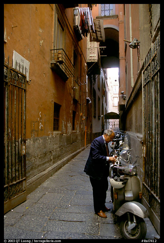 Man locking his motorbike in a side street. Naples, Italy