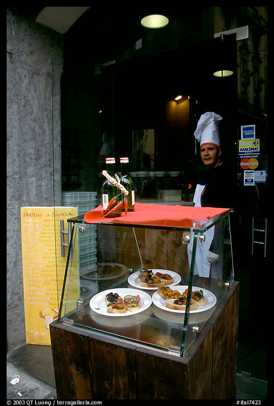 Chef at restaurant doorway with appetizers shown in glass case. Naples, Campania, Italy