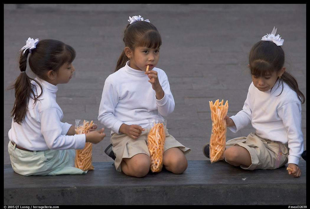 Three little girls in school uniform eating snack. Guadalajara, Jalisco, Mexico