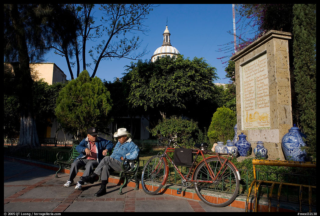 Men sitting in garden, with cathedral dome and ceramic monument, Tlaquepaque. Jalisco, Mexico