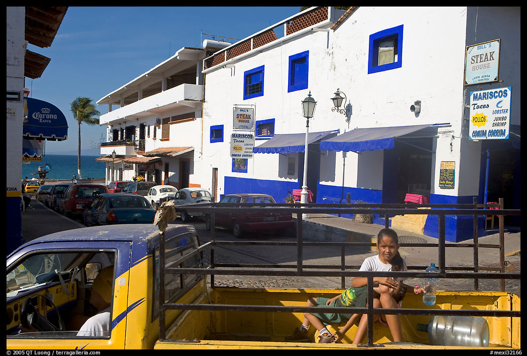 Girl riding in the back of pick-up truck in a street close to ocean, Puerto Vallarta, Jalisco. Jalisco, Mexico