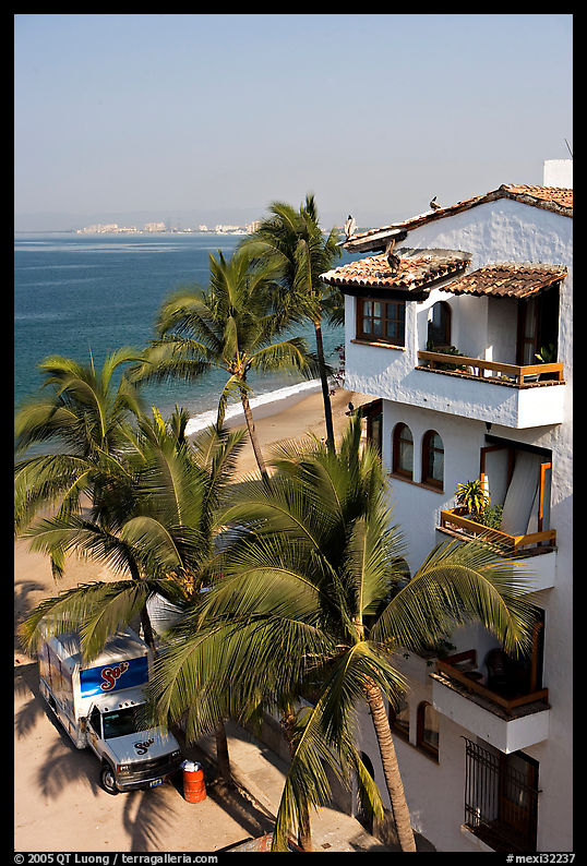 White adobe building with red tile roof,  palm trees and ocean, Puerto Vallarta, Jalisco. Jalisco, Mexico