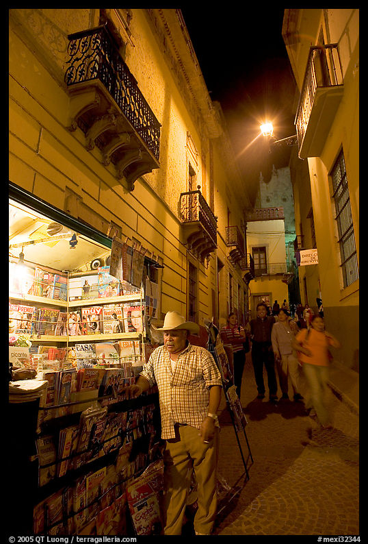 Man at a Newstand booth in a narrow callejone at night. Guanajuato, Mexico