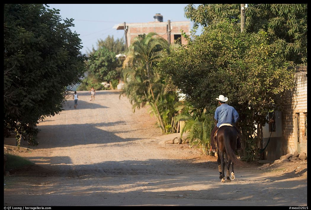 Man on horse going down a village street. Mexico