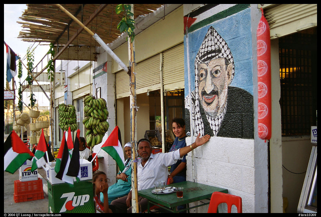 Palestinian cafe owner pointing proudly to a painting of Yasser Arafat, Jericho. West Bank, Occupied Territories (Israel)
