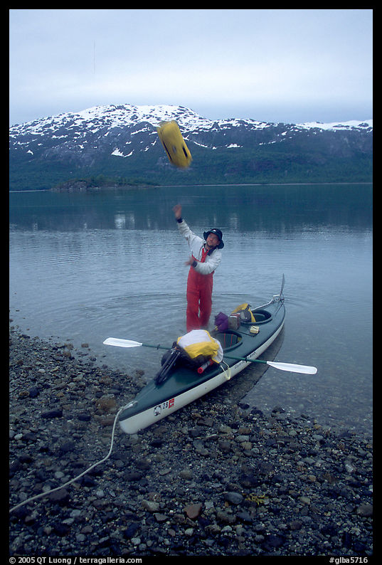 Kayaker unloading the kayak by throwing stuff sacks out. Glacier Bay National Park, Alaska