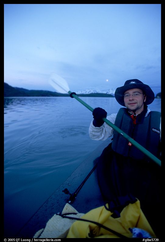 Kayaker paddling in Muir Inlet at midnight. Glacier Bay National Park, Alaska