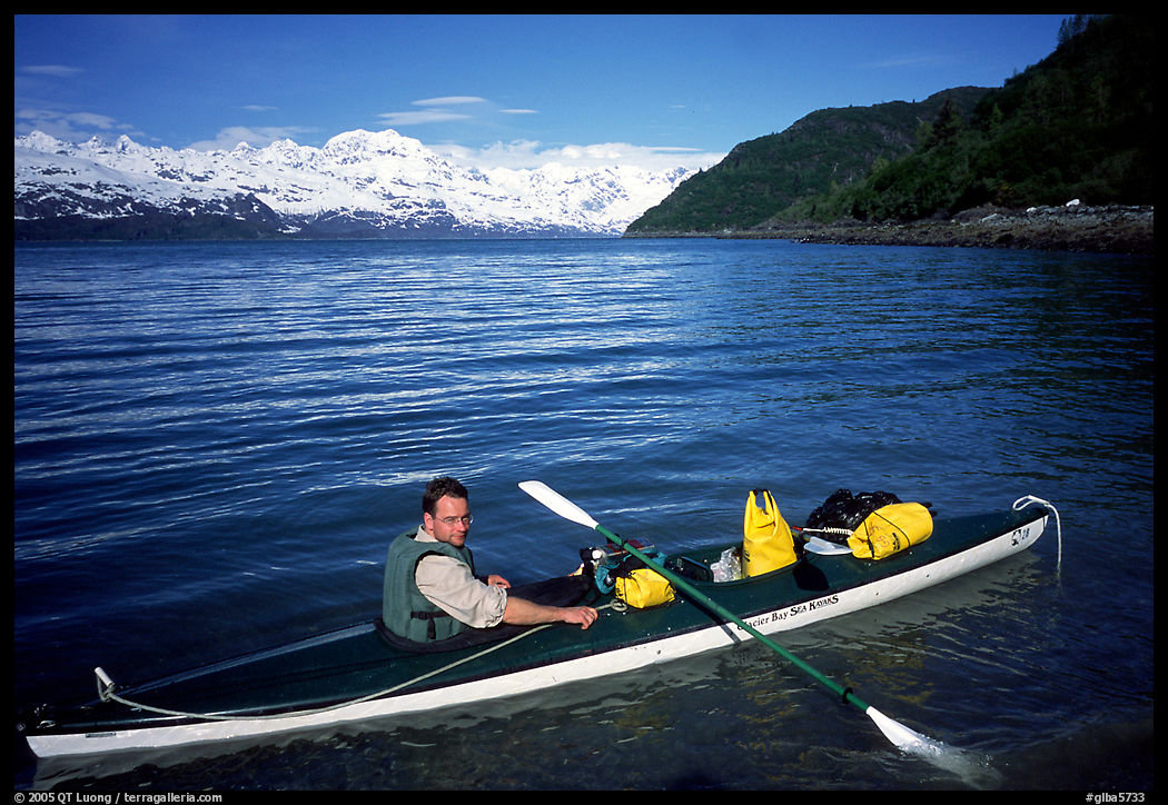 Kayaker sitting at a rear of a double kayak with the Fairweather range in the background. Glacier Bay National Park, Alaska