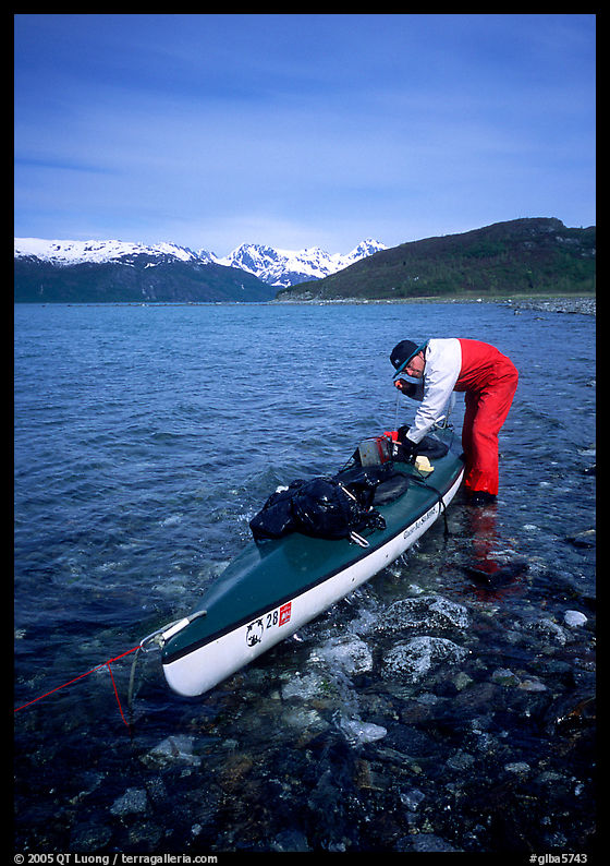 Kayaker tying up gear on top of the kayak,  East Arm. Glacier Bay National Park, Alaska