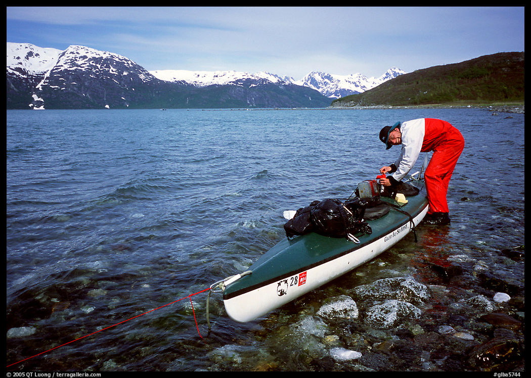 Kayaker tying up gear on top of the kayak,  East Arm. Glacier Bay National Park, Alaska