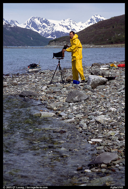 Large format photographer wearing kayaking gear on a beach in East Arm. Glacier Bay National Park, Alaska