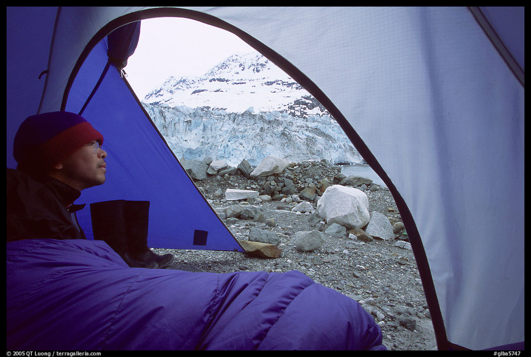 Camper lying in sleeping bag looks at Lamplugh Glacier. Glacier Bay National Park, Alaska