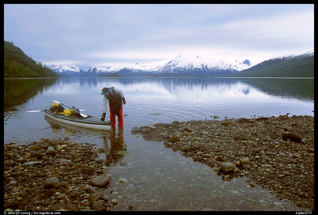 Kayaker standing in Scidmore Bay next to a shallow tidal channel. Glacier Bay National Park, Alaska
