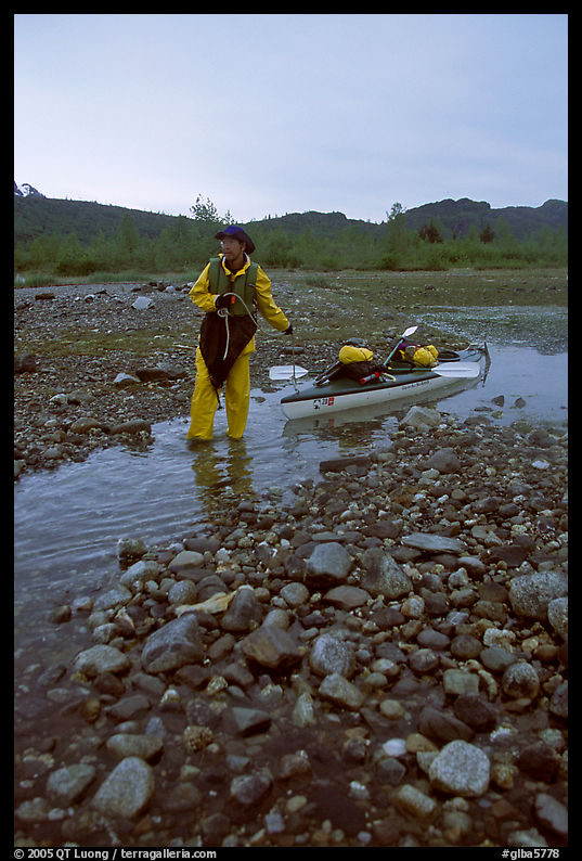 Kayaker towing the kayak in the narrowest part of a tidal channel into Scidmore Bay. Glacier Bay National Park, Alaska