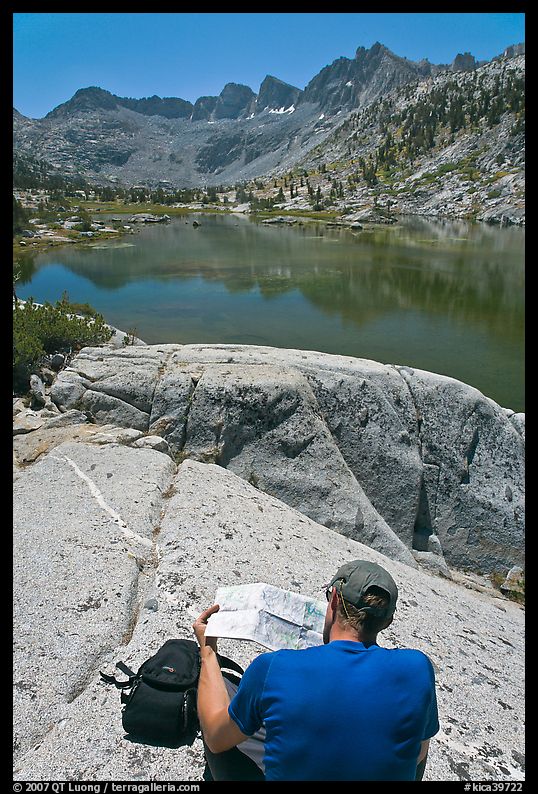 Hiker looking at map in front of lake, lower Dusy Basin. Kings Canyon National Park, California
