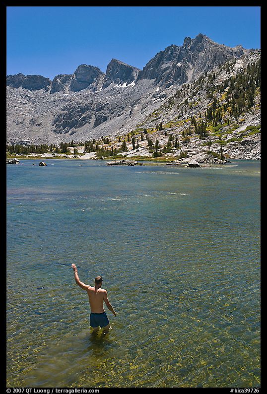 Man standing in alpine lake, lower Dusy Basin. Kings Canyon National Park, California