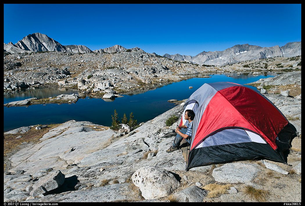 Man sitting in tent above lake, Dusy Basin. Kings Canyon National Park, California