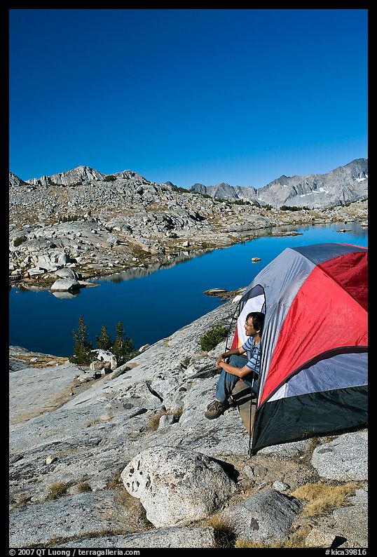 Man looking out from tent above lake, morning, Dusy Basin. Kings Canyon National Park, California