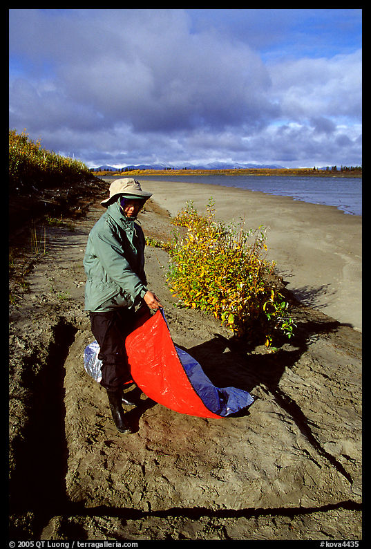 Camper folding the tarp while breaking camp. Kobuk Valley National Park, Alaska