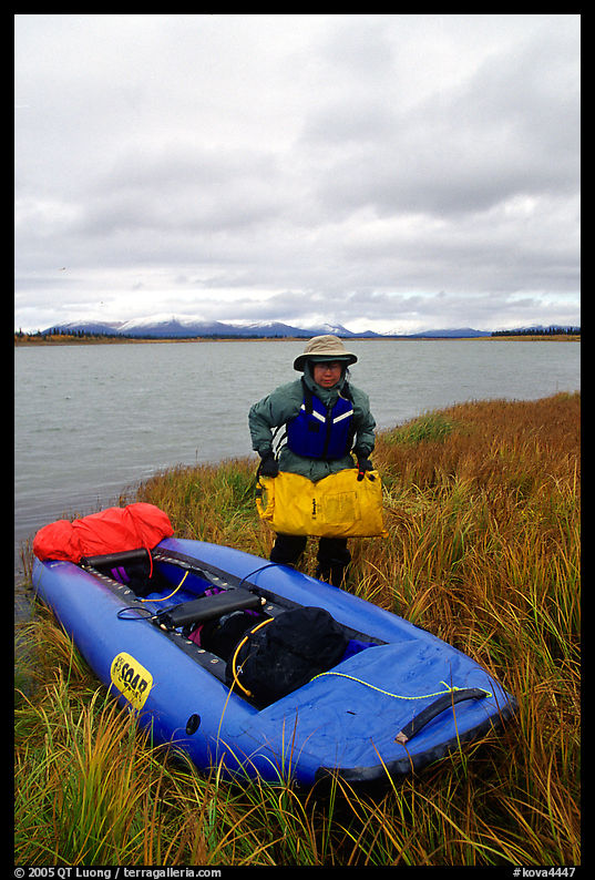 Canoeist unloading the canoe on a grassy riverbank. Kobuk Valley National Park, Alaska
