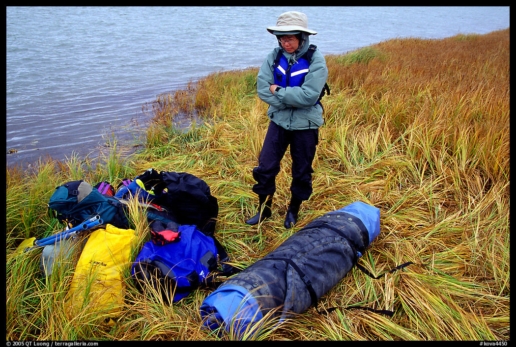 Canoeist standing next to gear and deflated and folded  canoe. Kobuk Valley National Park, Alaska