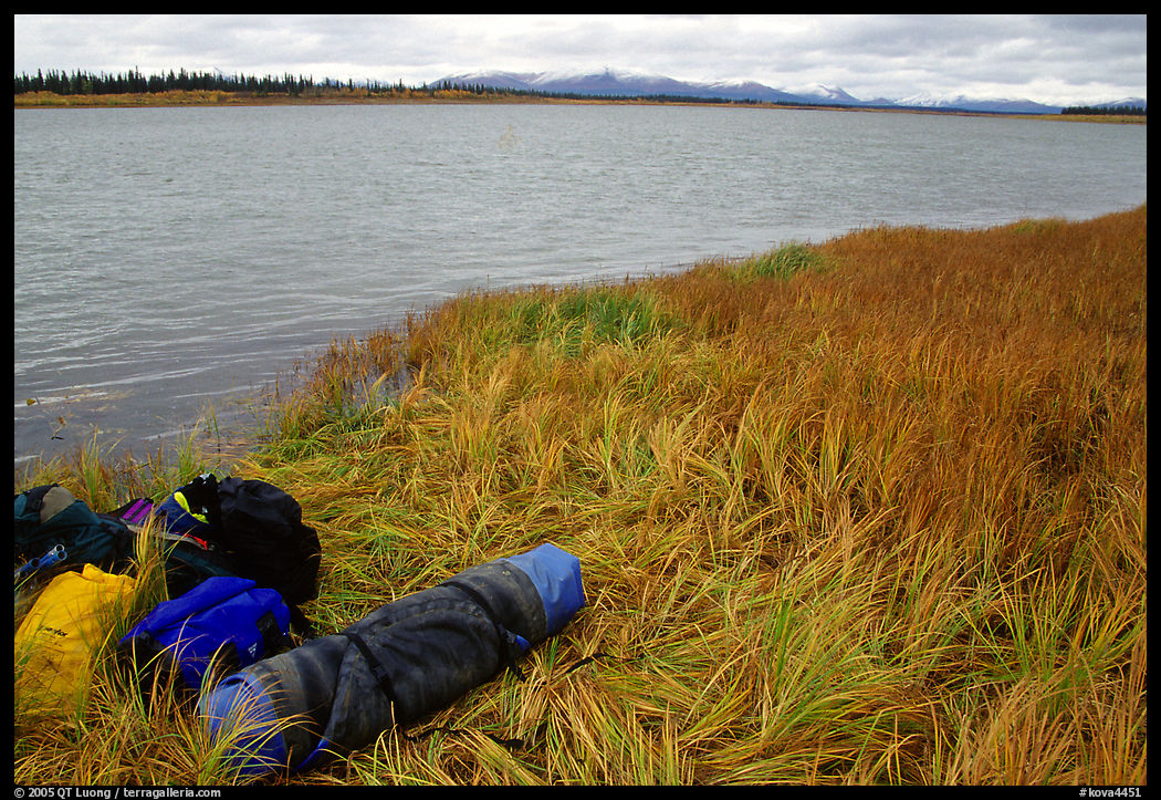 Gear and folded  canoe on a grassy riverbank of the Kobuk River. Kobuk Valley National Park, Alaska