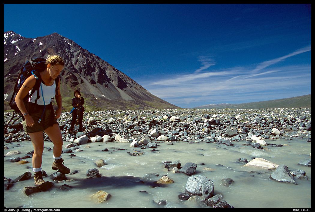 Hiker crossing a stream next to Lake Turquoise. Lake Clark National Park, Alaska