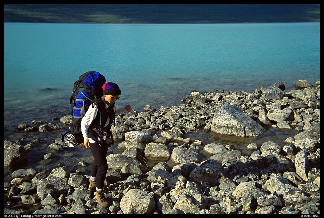 Backpacker walking on rocks on the shore of Turquoise Lake. Lake Clark National Park, Alaska