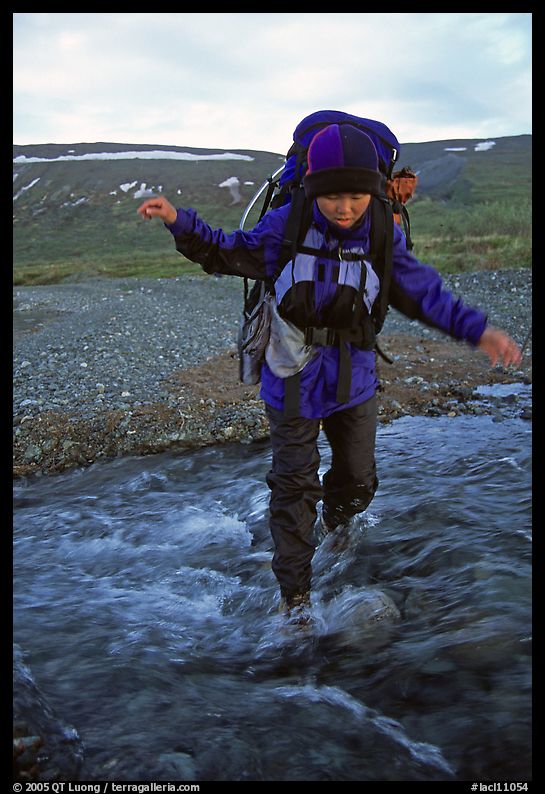 Backpacker balancing herself while crossing a stream. Lake Clark National Park, Alaska
