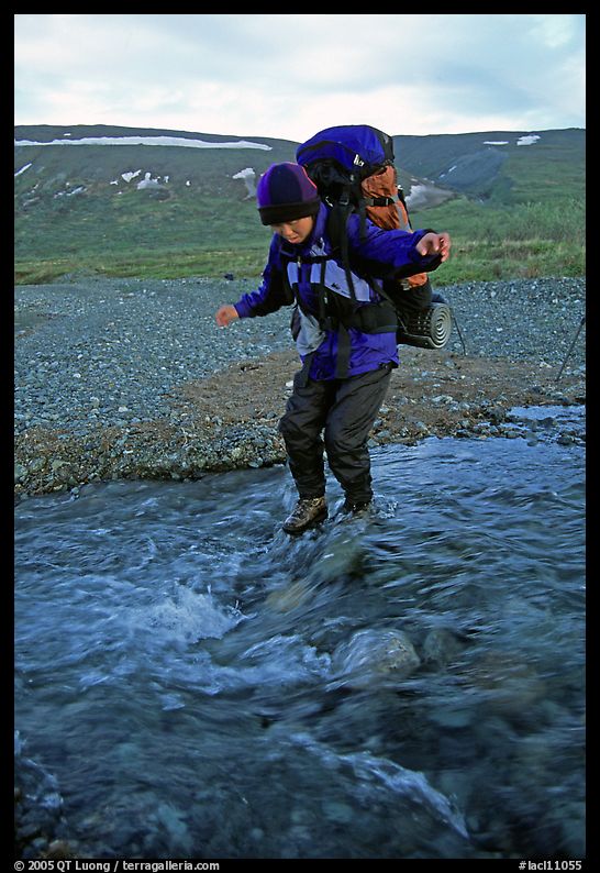 Backpacker crossing a stream on pebbles. Lake Clark National Park, Alaska