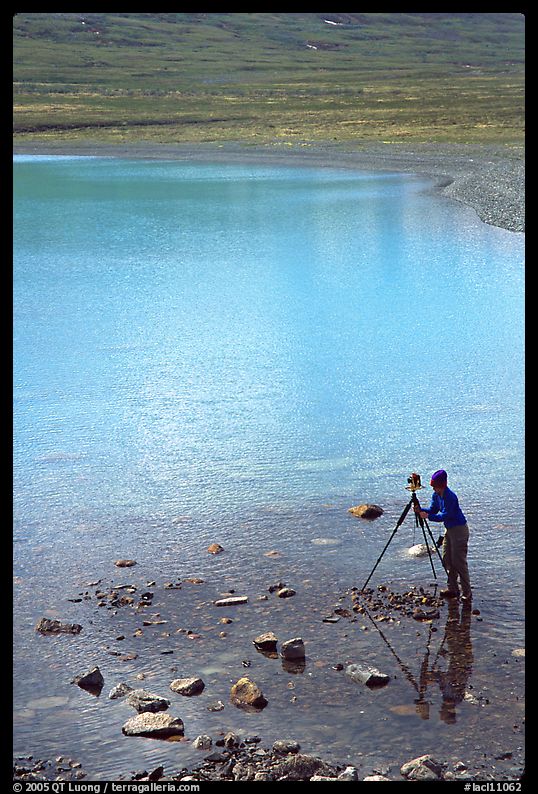 Large format photographer with tripod on the shores of Turquoise Lake. Lake Clark National Park, Alaska